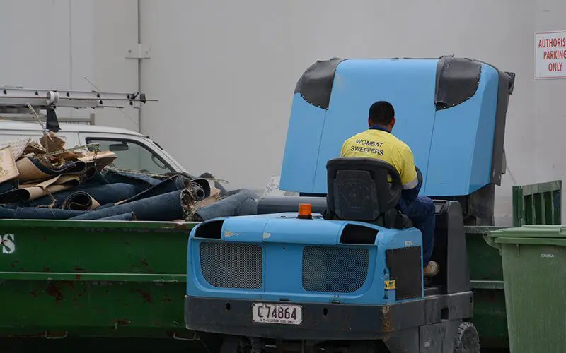 Emptying a sweeper machine hopper